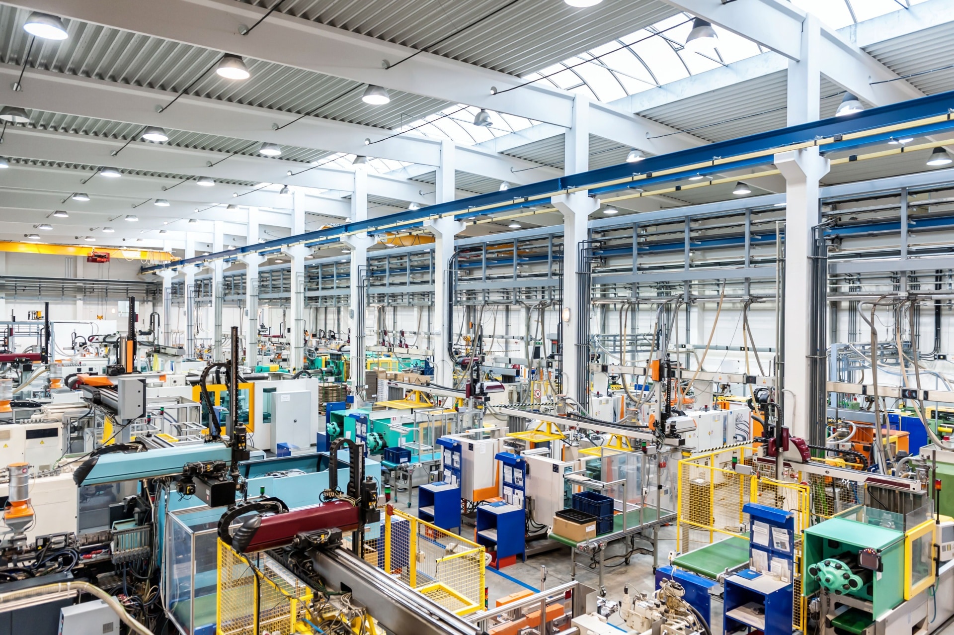 Ein hell erleuchtetes, großes industrielles Fabrikinterieur mit Reihen von Maschinen, Geräten und Arbeitsplätzen, die unter einer hohen Decke mit Oberlichtern übersichtlich angeordnet sind, unterstützt von modernen Energieanlagen für eine effiziente industrielle Energieversorgung.